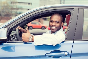 man driving car with thumbs up