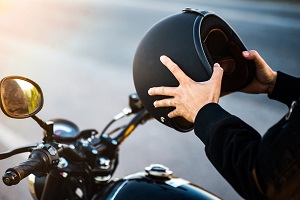 man sitting motorcycle putting helmet on