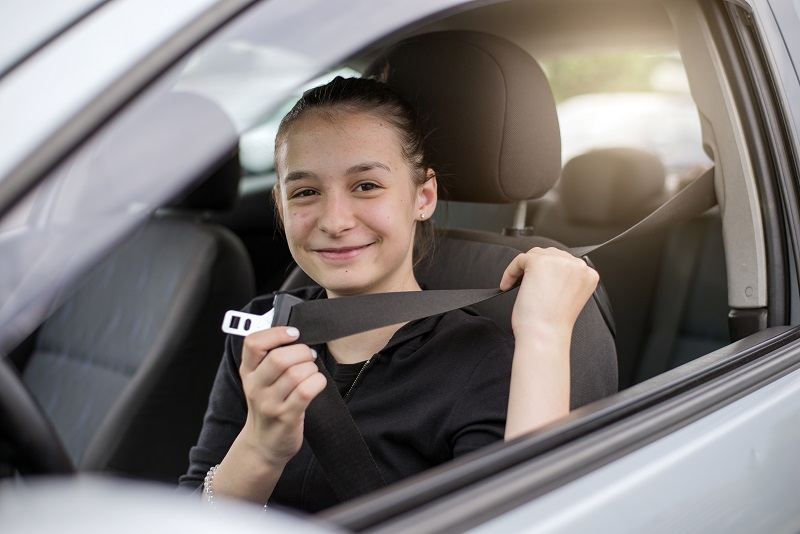 teen driver putting on seatbelt